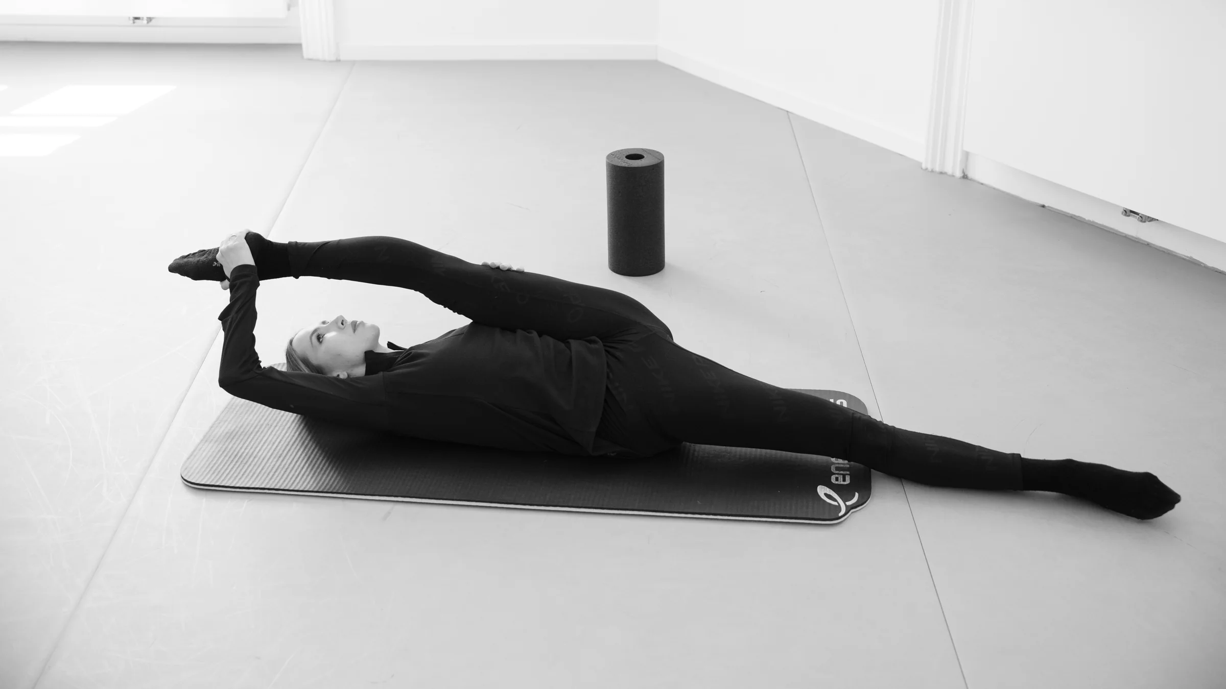 Eine Tänzerin liegt mit gestreckten Armen auf der Matte während einer Floor-Barre-Stunde bei ARTIS, Wien