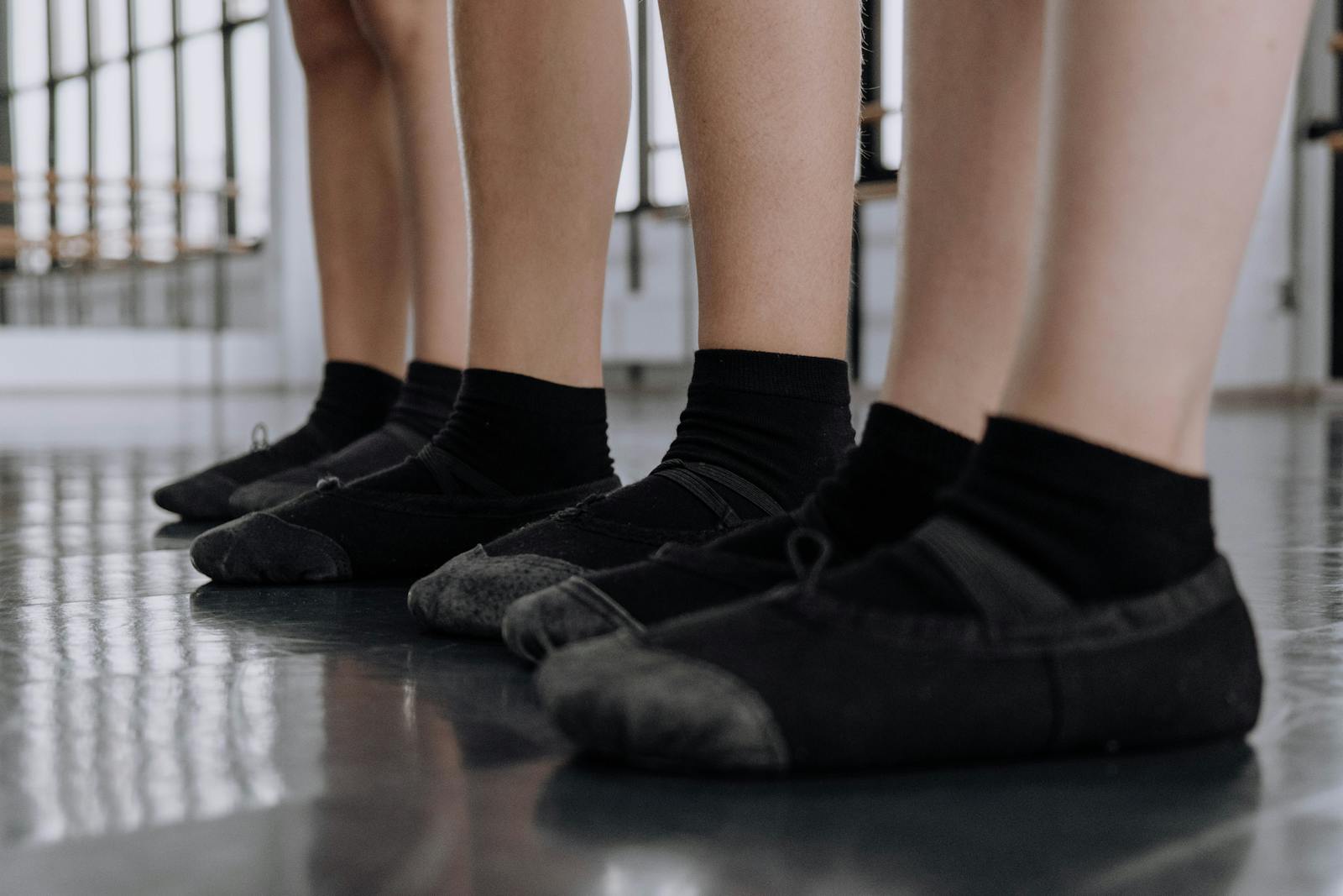 Small feet in soft black ballet shoes on a studio floor