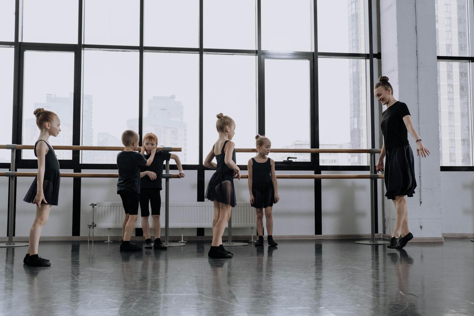 Young children at the barre in a candid ballet class — natural daylight, mixed-gender group