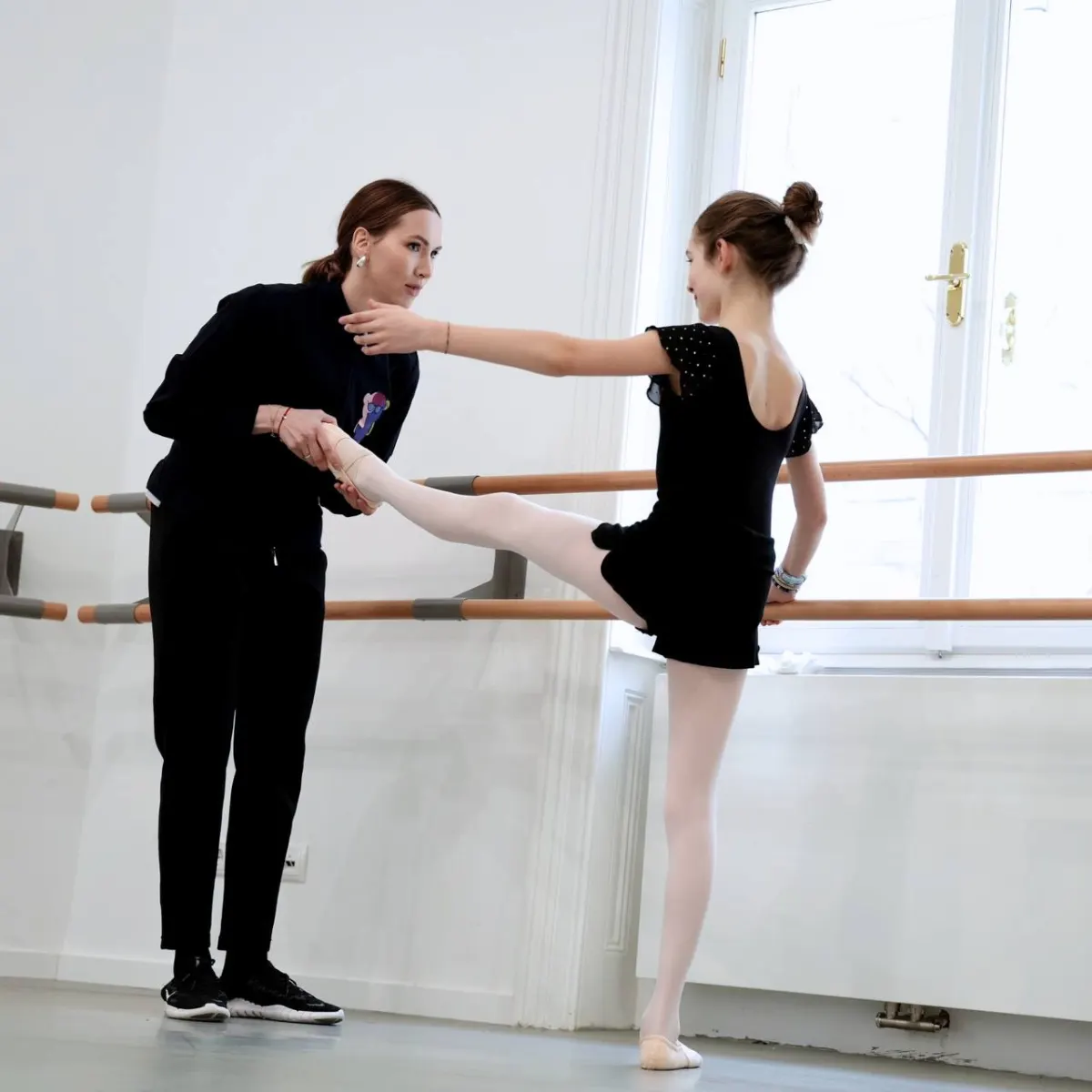Instructor guiding a student at the barre